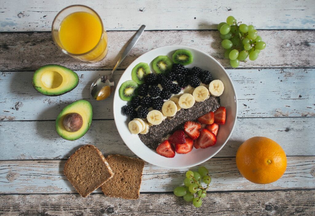 smoothie bowl with fruits, berries, chia seeds; avocado and whole grain bread